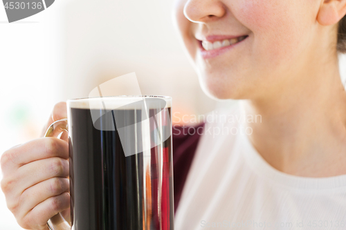 Image of close up of smiling woman with dark beer in mug