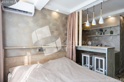 Image of View of the bed, bar and kitchen in a small hotel room