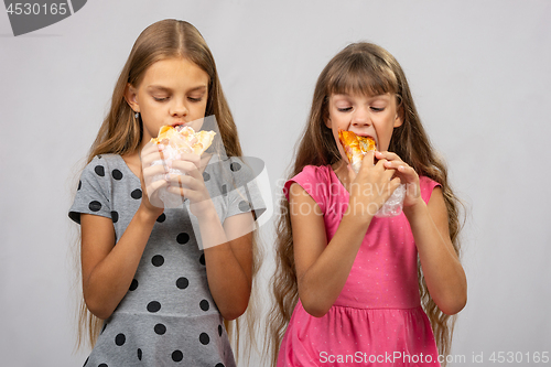 Image of Two hungry girls eat bread