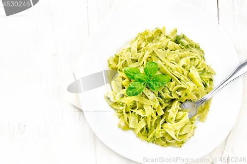 Image of Pasta with pesto sauce in plate on board top