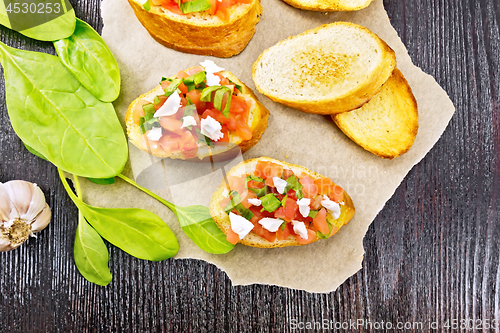 Image of Bruschetta with tomato and cheese on dark board top