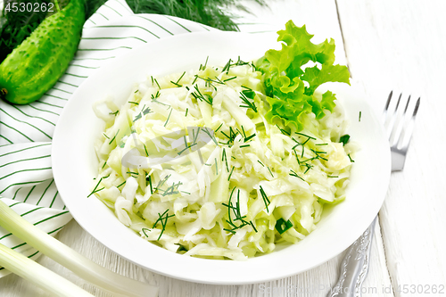Image of Salad of cabbage and cucumber in plate on white board