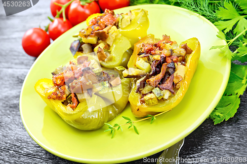 Image of Pepper stuffed with vegetables in green plate on dark wooden board