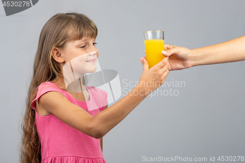 Image of The girl takes from her hand a glass of orange juice