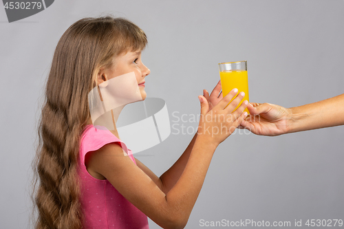 Image of The hand holds out a glass of orange juice
