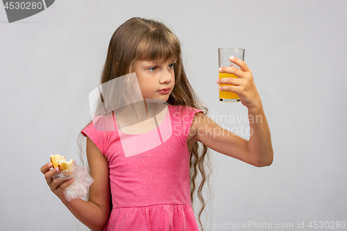 Image of The girl intently looks at a glass of juice