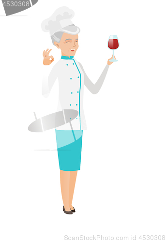 Image of Chef holding glass of wine and showing ok sign.