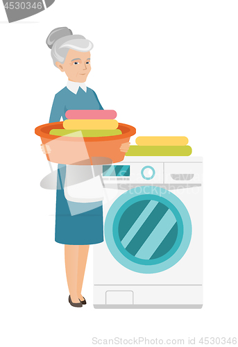 Image of Senior housewife using washing machine at laundry.