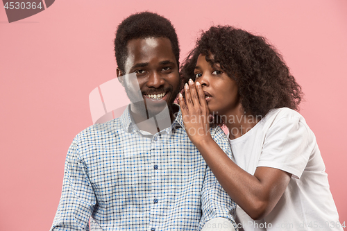 Image of The young woman whispering a secret behind her hand to afro man