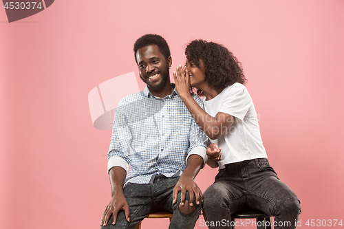 Image of The young woman whispering a secret behind her hand to afro man