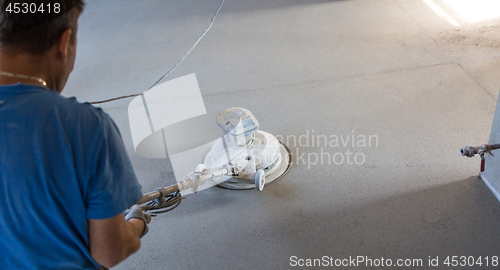 Image of Laborer polishing sand and cement screed floor.