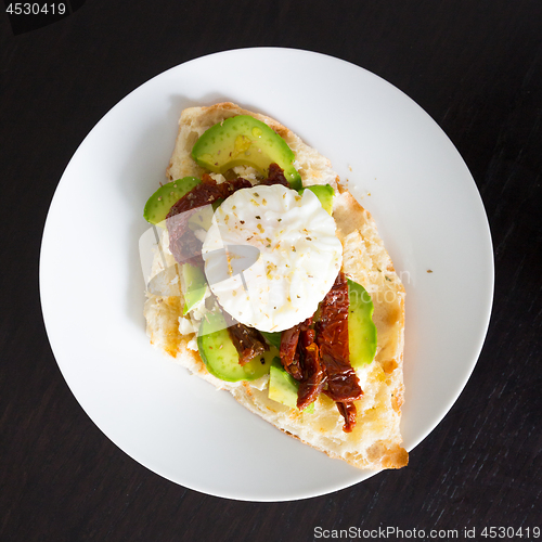 Image of Poached egg on a toasted bun with avocados and dried tomatoes