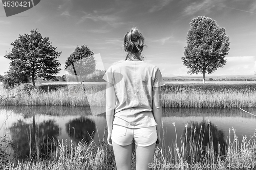 Image of Young woman wearing casual summer clothes enjoying beautiful view of peaceful countryside.