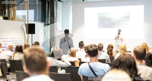 Image of Businessman in audience standing and asking question to speeker at business conference.