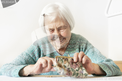 Image of Cheerful elderly 96 years old woman sitting at table at home happy with her pension savings in her wallet after paying bills.