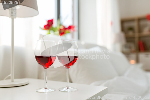 Image of two glasses of wine on bedroom nightstand at home