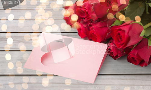 Image of close up of red roses and greeting card with heart