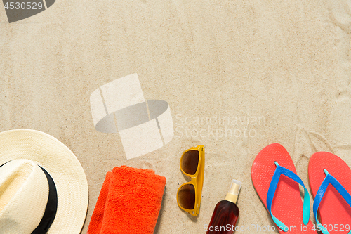 Image of straw hat, flip flops and sunglasses on beach sand