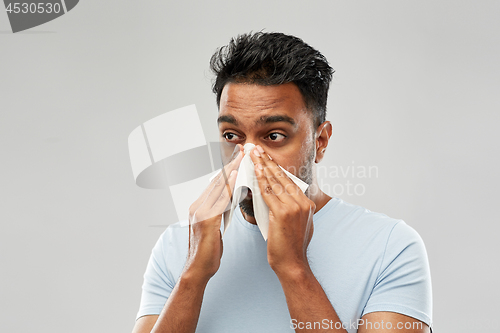 Image of indian man with paper napkin blowing nose