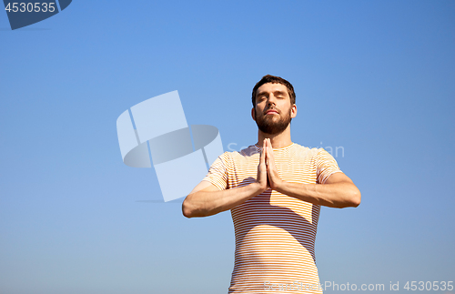 Image of man meditating outdoors over sky