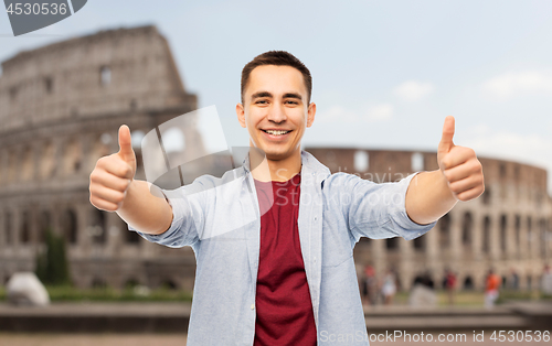Image of happy young man showing thumbs up over coliseum