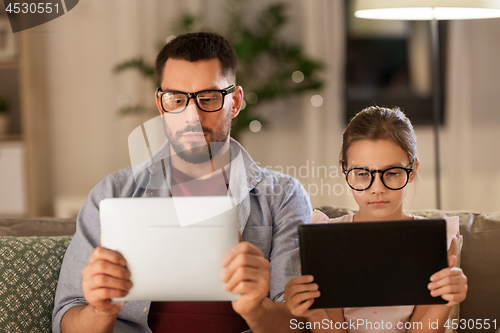 Image of father and daughter with tablet computers at home