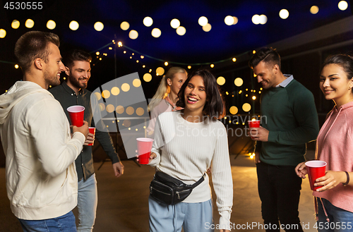 Image of friends with drinks dancing at rooftop party