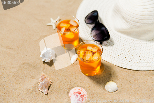 Image of cocktails, sun hat and sunglasses on beach sand