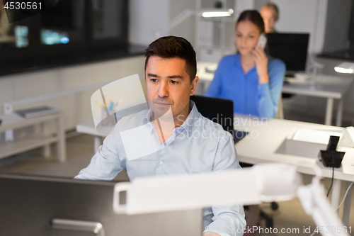 Image of man with computer working at night office