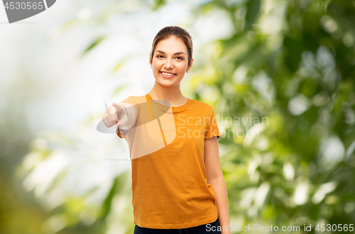 Image of teenage girl pointing at you over natural backdrop