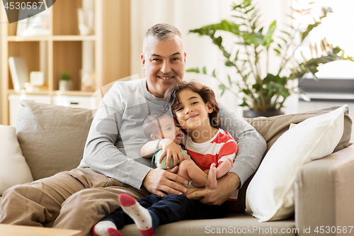 Image of happy father with preteen and baby son at home