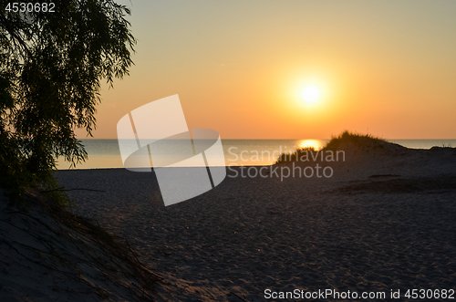 Image of Sunset by an empty sandy beach