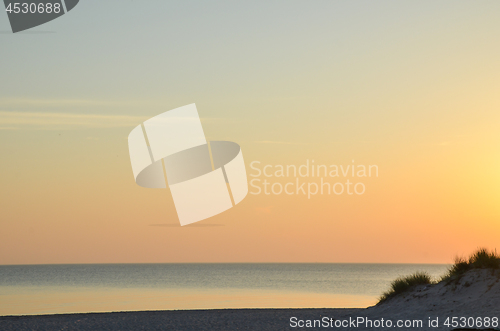 Image of Colorful sky by a sandy beach by sunset