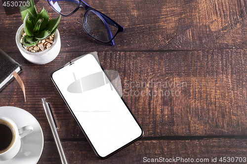 Image of Working table with smart phone notepad coffee cup pen glasses pl