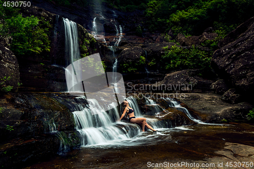 Image of Woman basking in lush mountain waterfall