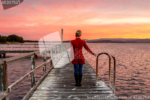 Image of Woman on rustic timber jetty watching beautiful sunset