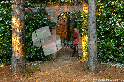 Image of Woman standing in beautiful stone garden arch