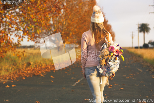 Image of Woman walking along a country road in Autumn