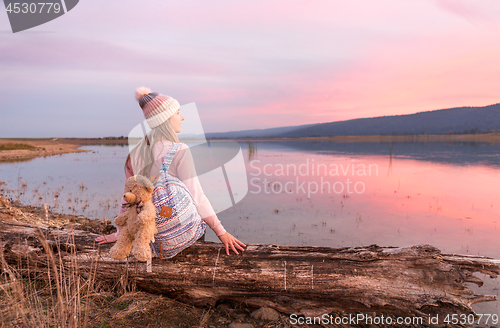 Image of Relaxed woman watching a serene sunset by the lake