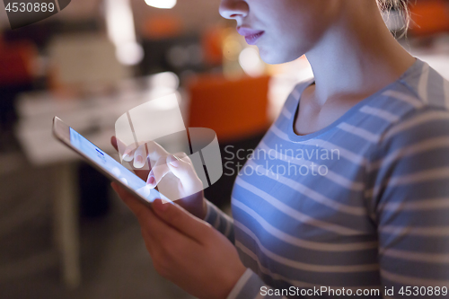 Image of woman working on digital tablet in night office