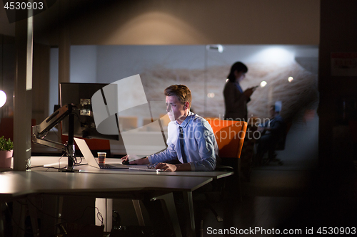 Image of man working on computer in dark office