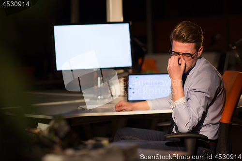 Image of man working on computer in dark office