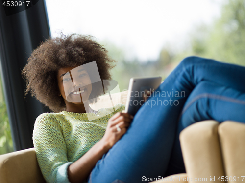 Image of young african american woman at home using digital tablet