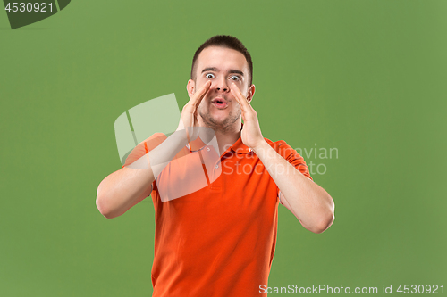 Image of Isolated on green young casual man shouting at studio