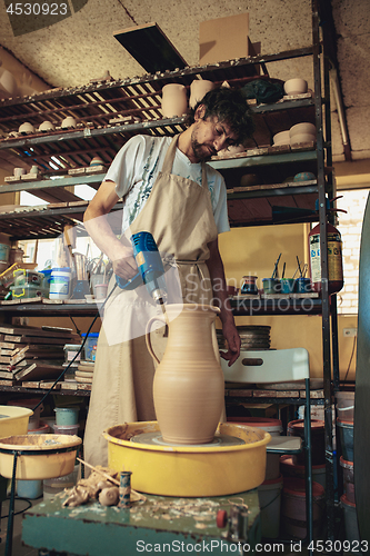 Image of Creating a jar or vase of white clay close-up. Master crock.