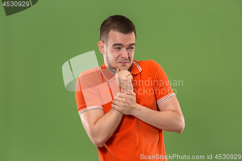 Image of Let me think. Doubtful pensive man with thoughtful expression making choice against green background