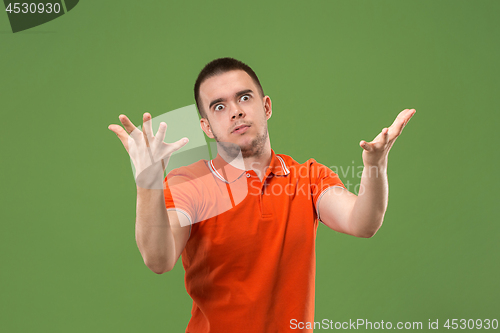 Image of Beautiful male half-length portrait isolated on green studio backgroud. The young emotional surprised man