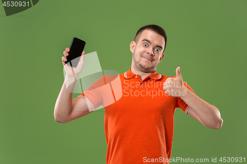 Image of The happy man showing at empty screen of mobile phone against green background.
