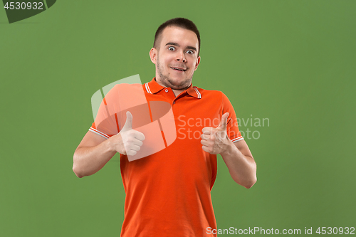 Image of The happy businessman standing and smiling against green background.