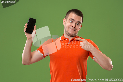 Image of The happy man showing at empty screen of mobile phone against green background.